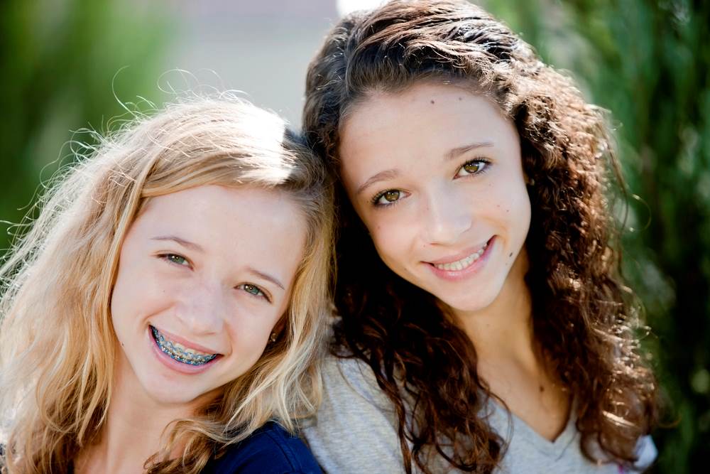 Image of two smiling Caucasian teenage girls in a park, featuring Lakewood Child and Family Counseling and highlighting online therapy support for teenagers in Washington.